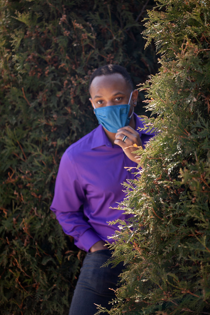 Lateef, hiding in the bushes, wearing a pandemic mask