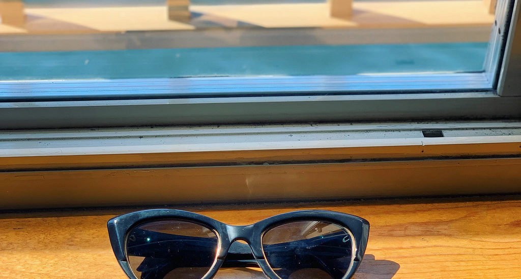 Sunglasses on a window ledge near water