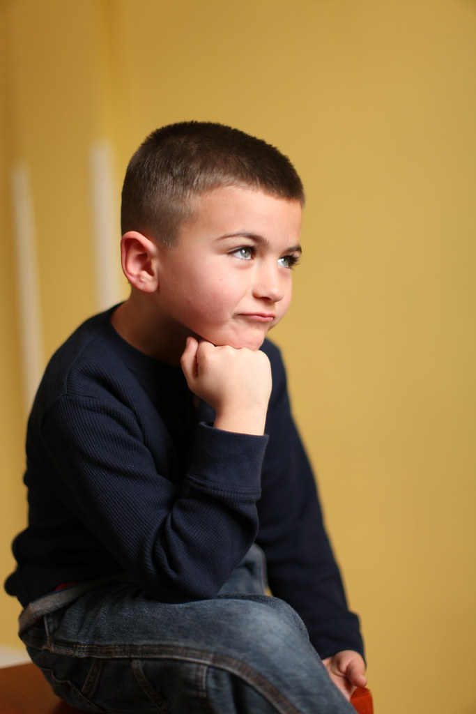 A young boy posing in profile with his chin resting on his fist