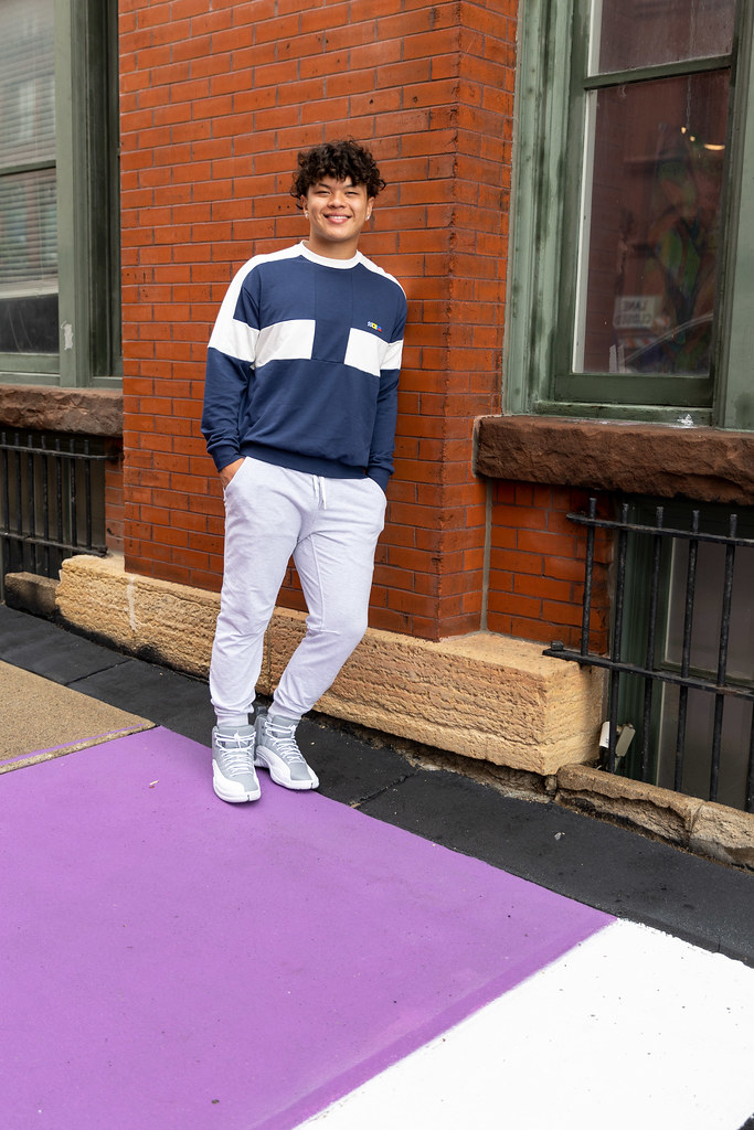 A young man leaning against a brick wall while standing on a colorfully painted sidewalk